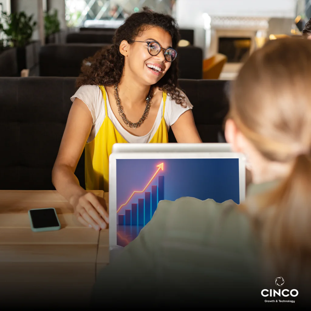 Duas mulheres sentadas, cada uma de frente para o seu computador.